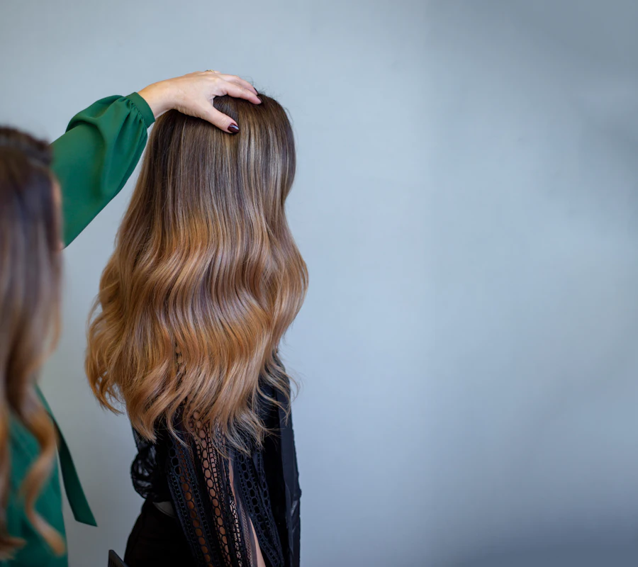 Peluquera peinando una melena castaña con reflejos